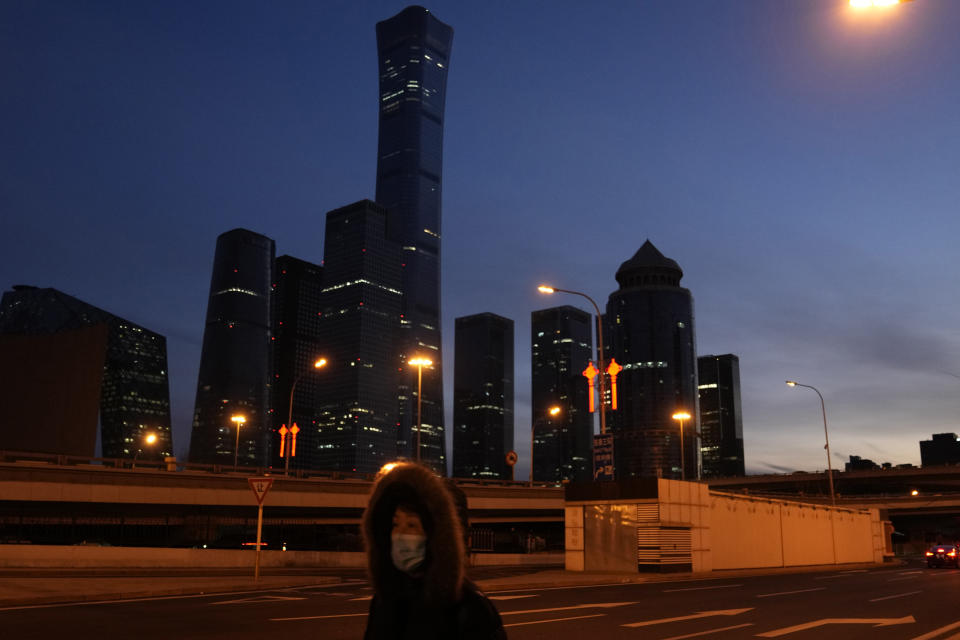 A resident wearing a mask to protect from the coronavirus walk past the central business district in Beijing, China, Wednesday, Jan. 26, 2022. Richer, more heavily armed and openly confrontational, China has undergone history-making change since the last time it was an Olympic host in 2008. (AP Photo/Ng Han Guan)