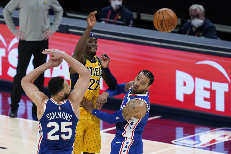 Indiana Pacers' Caris LeVert (22) makes a pass against Philadelphia 76ers' Ben Simmons (25) and Mike Scott during the second half of an NBA basketball game, Tuesday, May 11, 2021, in Indianapolis. Indiana won 103-94. (AP Photo/Darron Cummings)