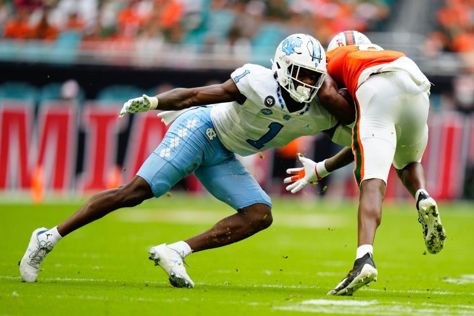 Oct 8, 2022; Miami Gardens, Florida, USA; North Carolina Tar Heels defensive back Tony Grimes (1) tackles Miami Hurricanes wide receiver Frank Ladson Jr. (8) during the first half at Hard Rock Stadium. Mandatory Credit: Rich Storry-USA TODAY Sports