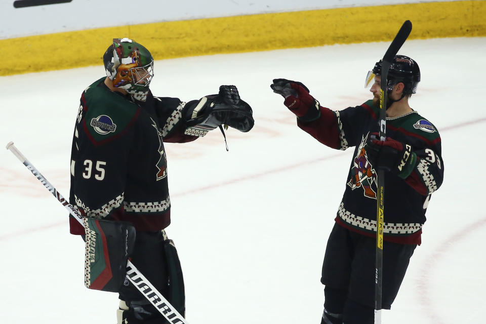 Arizona Coyotes goaltender Darcy Kuemper (35) celebrates a win against the Chicago Blackhawks with Coyotes defenseman Alex Goligoski (33) as time expires during the third period of an NHL hockey game Thursday, Dec. 12, 2019 in Glendale, Ariz. The Coyotes defeated the Blackhawks 5-2. (AP Photo/Ross D. Franklin)