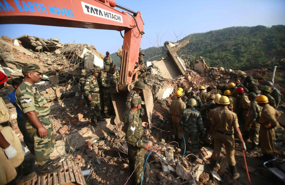 Indian army soldiers and fire officials look for survivors from the debris of a building that collapsed in Canacona, about 70 kilometers (44 miles) from Goa state capital Panaji, India, Sunday, Jan. 5, 2014. The five-story building under construction in the southern Indian state of Goa collapsed on Saturday, killing at least a dozen people and leaving dozens more feared trapped under the rubble, police said. (AP Photo/Rafiq Maqbool)