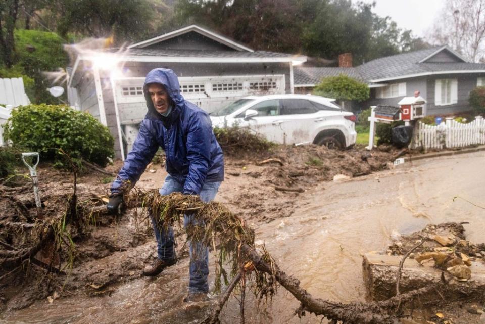 A man clears debris from a mudslide at his parent’s home. AP