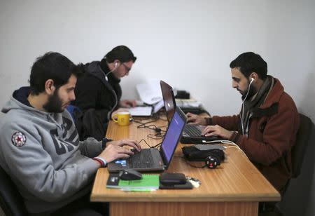 Palestinian employees process data on their laptops at Unit One in Gaza City January 15, 2015. REUTERS/Mohammed Salem