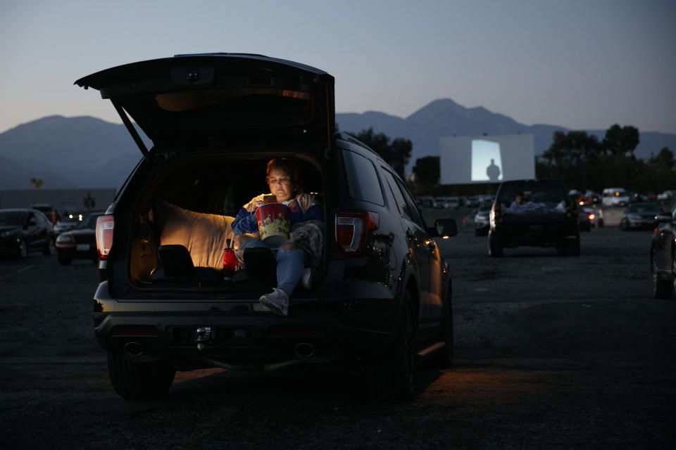 FILE - Serena Benavidez looks at her smartphone while waiting for a movie to start at Mission Tiki drive-in theater in Montclair, Calif., on May 28, 2020. About 1,000 theaters in the U.S. are currently open, or about a sixth of the nation’s cinemas. That includes approximately 300 drive-ins. Mission Tiki, the four-screen, Polynesian-themed drive-in, turned into the epicenter of U.S. moviegoing. (AP Photo/Jae C. Hong, file)