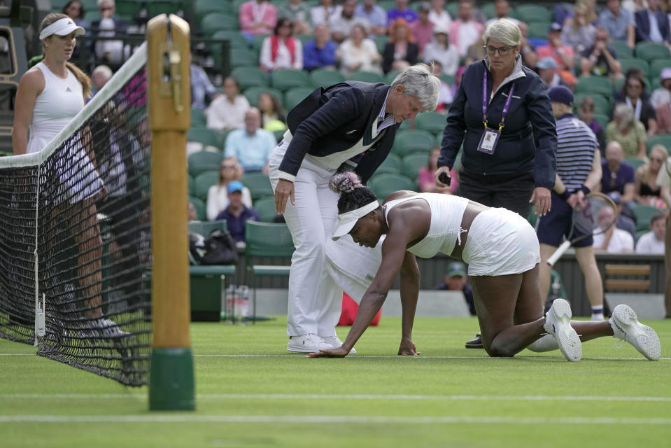 Officials assist after Venus Williams of the US slipped as she plays Ukraine's Elina Svitolina, left, in a first round women's singles match on day one of the Wimbledon tennis championships in London, Monday, July 3, 2023. (AP Photo/Kin Cheung)