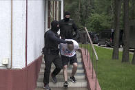 In this photo taken from video released by Belarusian KGB, State TV and Radio Company of Belarus on Wednesday, July 29, 2020, a Belarusian KGB officer detains a Russian man in a sanitarium outside in Minsk, Belarus. Belarusian officials said that more than 30 detained employees of private Russian military contractor Wagner are facing a criminal probe on charges of plotting terror attacks in Belarus amid a presidential election campaign. (Belarusian KGB, State TV and Radio Company of Belarus via AP)