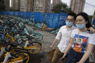 Residents wearing masks to curb the spread of the new coronavirus walk pasts rows of bicycles from bike-sharing services on the streets of Beijing, Saturday, May 30, 2020. (AP Photo/Ng Han Guan)