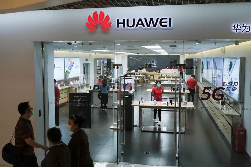 People wearing face masks walk past a Huawei store at a shopping mall, following an outbreak of the coronavirus disease (COVID-19), in Beijing