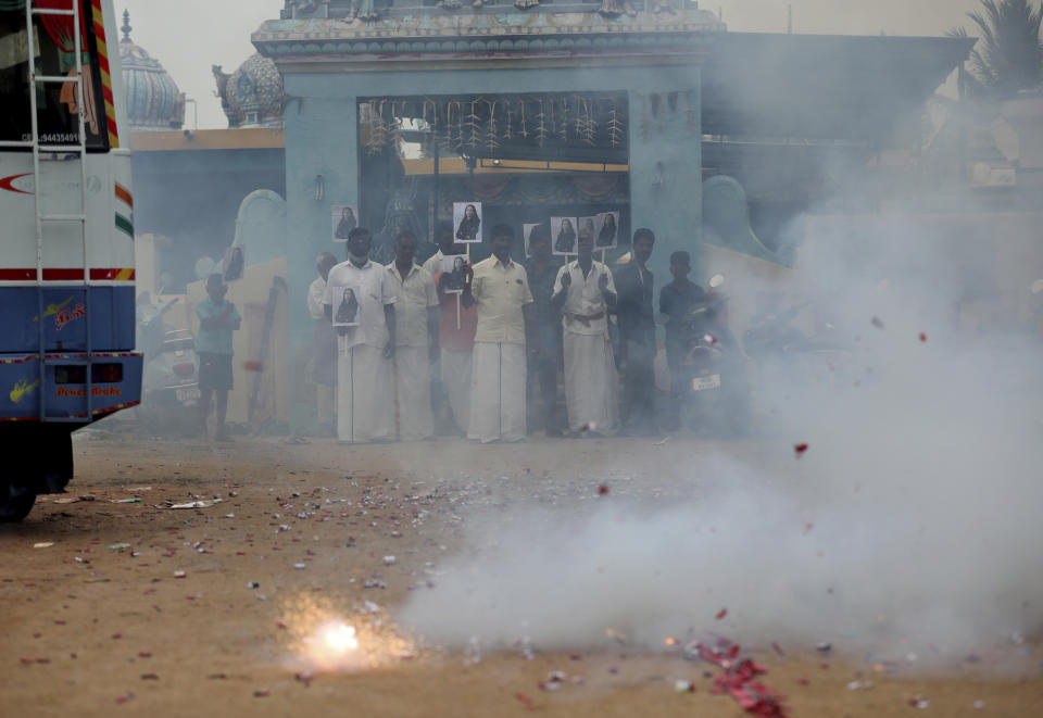 Villagers burst firecrackers and hold placards featuring U.S. Vice President-elect Kamala Harris ahead of her inauguration, in Thulasendrapuram, the hometown of Harris' maternal grandfather, south of Chennai, Tamil Nadu state, India, Wednesday, Jan. 20, 2021. A tiny, lush-green Indian village surrounded by rice paddy fields was beaming with joy Wednesday hours before its descendant, Kamala Harris, takes her oath of office and becomes the U.S. vice president. (AP Photo/Aijaz Rahi)
