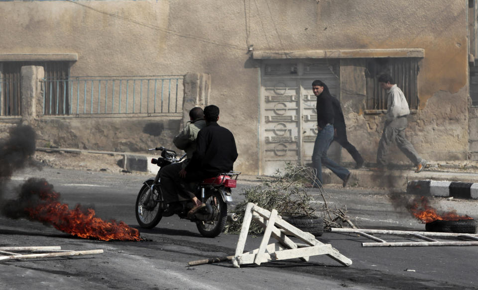 FILE - In this March 23, 2011, file photo, anti-government protesters pass burning tires set alight by the protesters following clashes with Syrian security forces in the southern city of Daraa, Syria. The decision by Syrian President Bashar Assad to crush the initially peaceful protests in March 2011 propelled Syria into a civil war that has killed more than a half million people. (AP Photo/Hussein Malla, File)