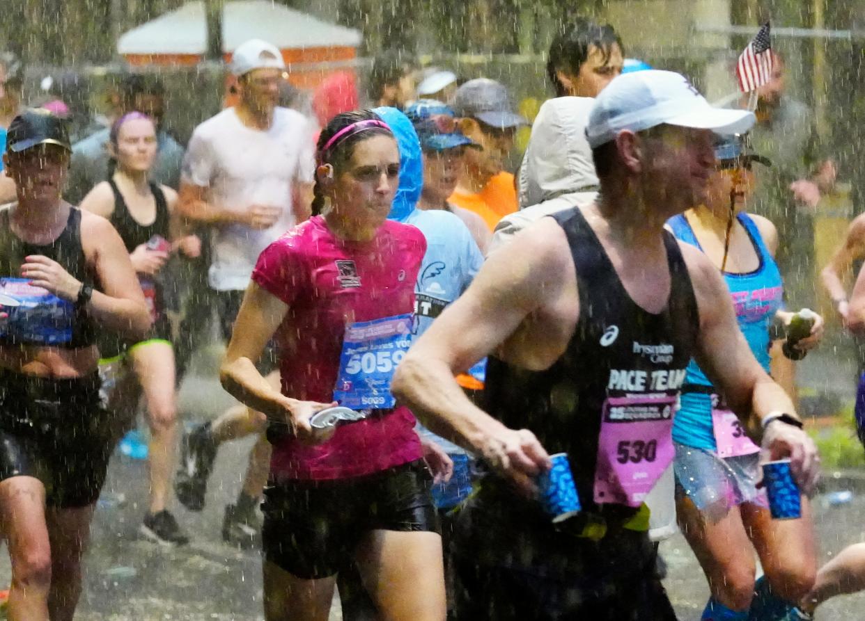 During a torrential downpour, along with thunder and lightning, runners make their way across Seventh Street in downtown Cincinnati, during the 2023 Cincinnati Flying Pig Marathon.