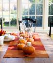 <p>One way to cast glimmering candlelight across the entire table? Top pumpkins with votives and shield the flames by securing glass hurricanes with floral U-pins.</p>