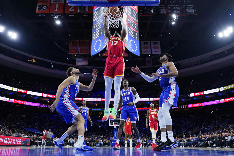 Atlanta Hawks' Onyeka Okongwu (17) goes up for a dunk between Philadelphia 76ers' Georges Niang (20) and Tobias Harris (12) during the second half of an NBA basketball game, Monday, Nov. 28, 2022, in Philadelphia. (AP Photo/Matt Slocum)