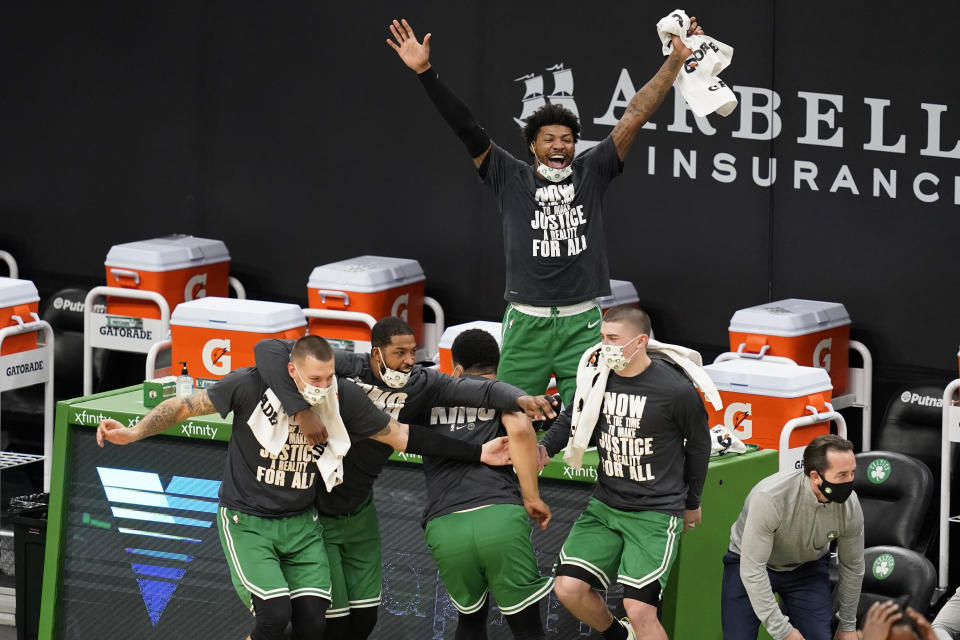 Boston Celtics guard Marcus Smart, top, and teammates on the bench celebrate a made basket by Tacko Fall during the fourth quarter of an NBA basketball game against the Orlando Magic, Friday, Jan. 15, 2021, in Boston. (AP Photo/Elise Amendola)