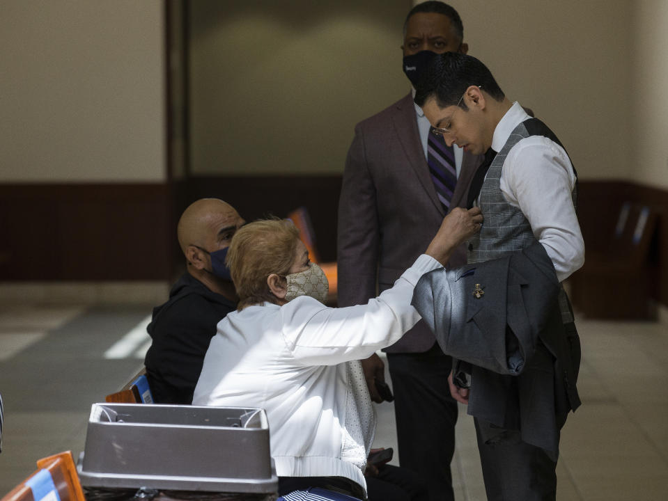 Victor Hugo Cuevas, a 26-year-old linked to a missing tiger named India, gets his tie adjusted by his grandmother, who did not wish to give her name, during a lunch break in the bond revocation hearing of a separate murder charge he's facing at Fort Bend County Justice Center on Friday, May 14, 2021, in Richmond, Texas. (Godofredo A. Vásquez/Houston Chronicle via AP)