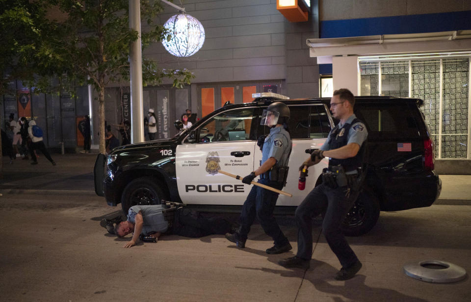 A Minneapolis police officer lies on the ground after being struck by an object Wednesday, Aug. 26, 2020 in Minneapolis. The Minneapolis mayor imposed a curfew Wednesday night and requested National Guard help after unrest broke out downtown following what authorities said was misinformation about the death of a Black homicide suspect. (Jeff Wheeler/Star Tribune via AP)