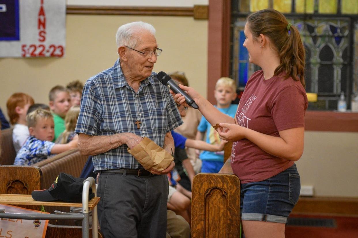 Chelsea Floro, right, asks Tony Picciuto to talk about the thousands of wooden crosses he has made and given away during Vacation Bible School at Solomon Lutheran Church on July 27. The VBS was a collaborative event hosted by Solomon and Woodville United Methodist Church. Picciuto was invited to celebrate his 100th birthday on July 28.