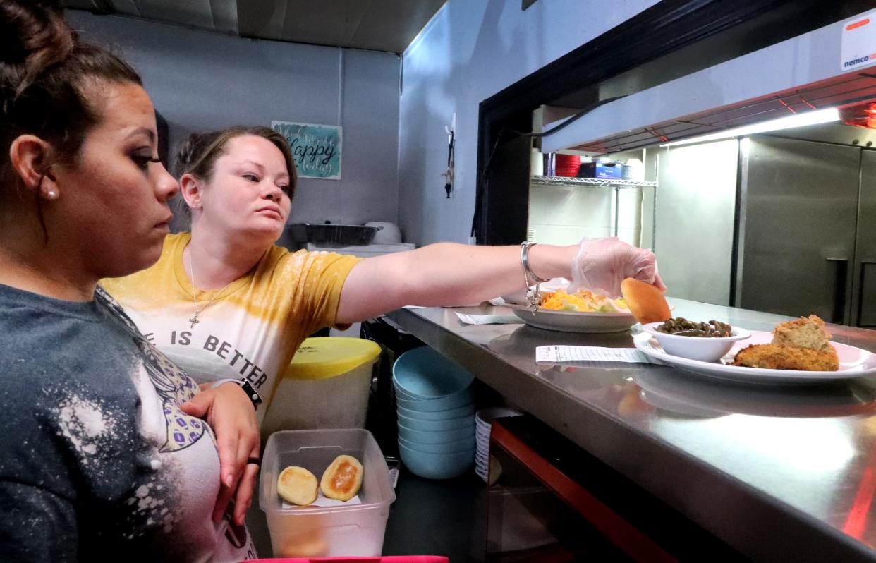 City Cafe waitress Staci Sewell, right reaches around waitress Cortney Adams on Wednesday, Aug. 31, 2022, at the restaurant to place a roll on the plate while Adams waits at the window for a to-go order. City Cafe is closed on Mondays including during Labor Day. Due to several local restaurants being closed on Labor Day customers will have to plan ahead.