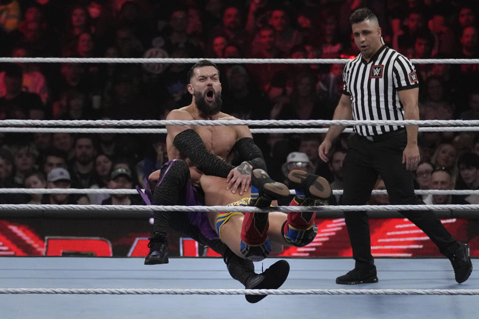 File - Wrester Finn Bálor, facing forward, is tackled by Johnny Gargano during the WWE Monday Night RAW event, Monday, March 6, 2023, in Boston. WWE is flexing its branding muscle, selling more than 90,000 tickets to next year's WrestleMania about eight months before the premium live event is held and before a single match has been announced. (AP Photo/Charles Krupa, File)