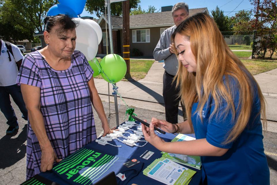 Christine Tran, right, shows Mary Alvarez how to download an app to operate a car-share vehicle at the E-Carshare preview event at Conway Homes in south Stockton on Thursday, August, 25, 2022.