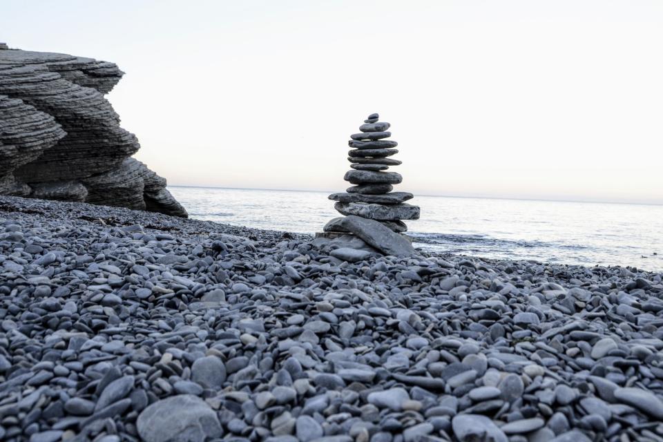 A cairn stands on the rock beach at Cap Bon Ami in Forillon National Park, Aug. 19, 2016, in Quebec, Canada. Against the ravaging seas, Quebec's coastal communities have learned through experience that the way to advance against climate change is to retreat. At Forillon, civilization has been pulled back from the water's edge where possible. (AP Photo/Cal Woodward)