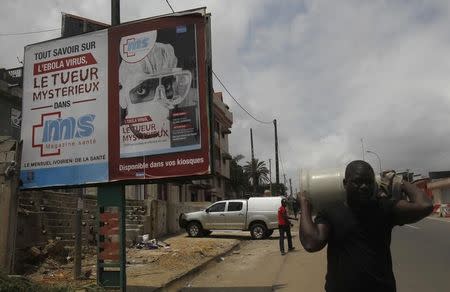 A man walks past a health magazine billboard, which reads: "Know everything about the Ebola virus, the mysterious killer", on a street in Abidjan September 10, 2014. REUTERS/Luc Gnago