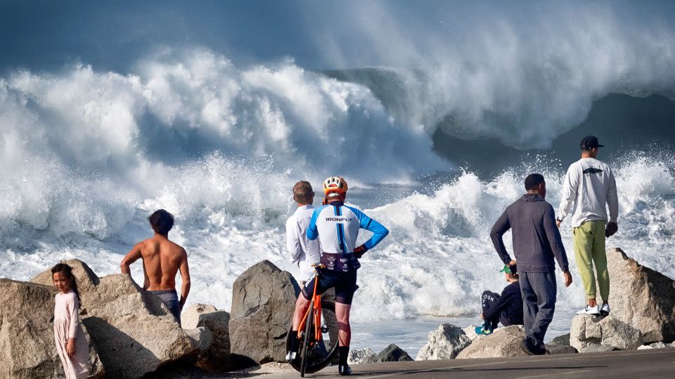 Beachgoers watch as huge surf pounds the coast in Manhattan Beach, California, on December 28, 2023. - Richard Vogel/AP
