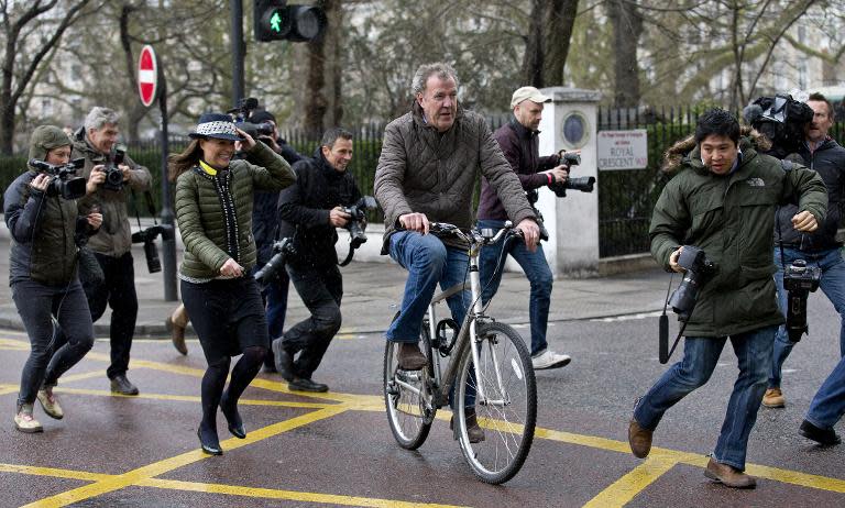 Television presenter Jeremy Clarkson (C) is surrounded by media as he leaves his home on a bicycle in London on March 26, 2015