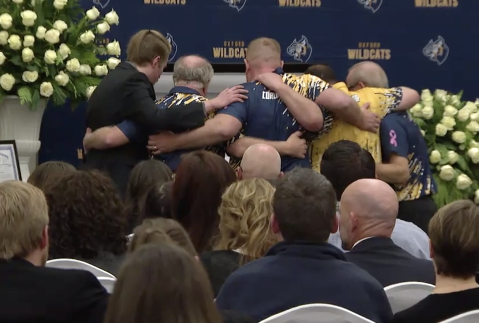 A group stands holding each other as they pay their respects during Oxford High School student Justin Shilling's funeral on Thursday, December 10, 2021.