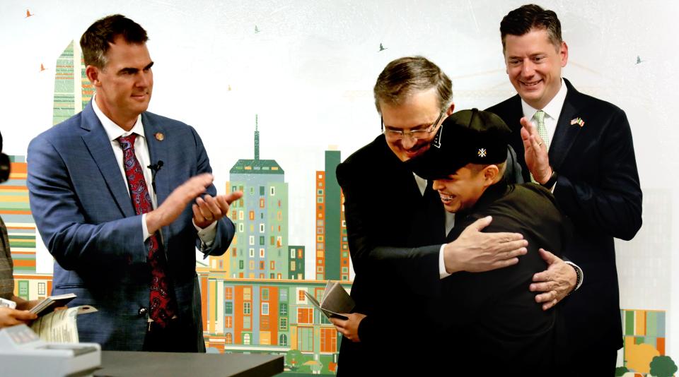 Gov. Kevin Stitt and Oklahoma City Mayor David Holt watch Saturday as Minister of Foreign Affairs of Mexico Marcelo Ebrard hugs Javier Rivera, the recipient of the first document, at the inauguration of Oklahoma City's Mexican consulate.