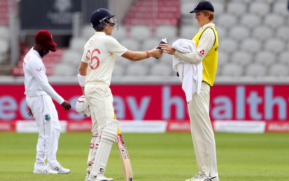 England's 12th man Zak Crawley (right) who has been dropped for the test match brings out drinks for Joe Root as he bats during day one of the Third Test at Emirates Old Trafford, Manchester. - PA