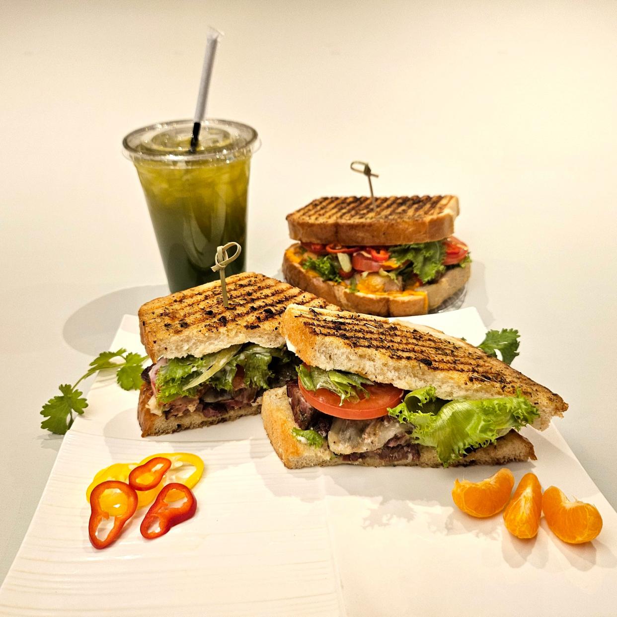 Cafe Rewind features a Baroness sandwich, front, spicy 3 Alarm Scorcher sandwich, back, and green apple and green tea drink.
