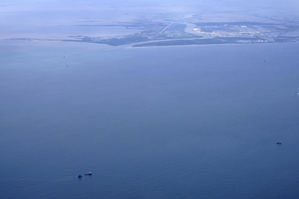 The capsized lift boat Seacor Power and two rescue boats, bottom left, are seen seven miles off the coast of Louisiana in the Gulf of Mexico Sunday, April 18, 2021. The vessel capsized during a storm on Tuesday. Port Fourchon and Bayou Lafourche, where the ship left port, are seen above. (AP Photo/Gerald Herbert)