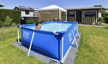 A camper enjoys the warm sunny weather in a pool at the Kerstgenshof camping park in Sonsbeck, Germany, Thursday, May 28, 2020. Germany's states, which determine their own coronavirus-related restrictions, have begun loosening lockdown rules to allow domestic tourists to return. (AP Photo/Martin Meissner)