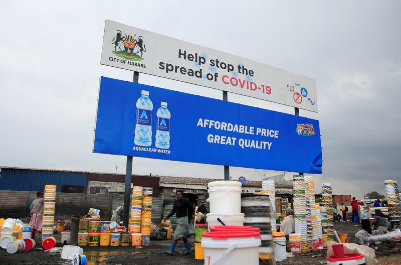 FILE PHOTO: Containers and other goods are sold beneath a coronavirus disease (COVID-19) awareness billboard in Harare