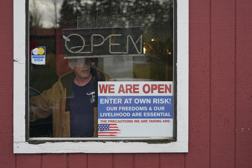 FILE - In this Jan. 4, 2021, file photo, a person walks through an entrance to the Farm Boy Drive-In restaurant during a protest rally near Olympia, Wash. The restaurant has been facing fines and penalties for continuing to offer inside dining despite current restrictions on the practice in Washington state due to the coronavirus pandemic. (AP Photo/Ted S. Warren, File)