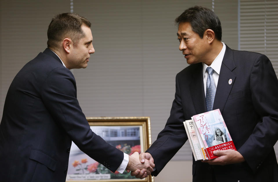 Israeli Embassy to Japan representative Peleg Lewi, left, shakes hands with Suginami Ward Mayor Ryo Tanaka as he hands over Anne Frank-related books to public libraries at the Suginami Ward Office in Tokyo Thursday, Feb. 27, 2014. The Israeli Embassy is donating 300 books after the recent vandalism of a similar number of such books in their collections. More than 300 books related to Anne Frank, including copies of "The Dairy of a Young Girl," have been found damaged in Tokyo libraries. Suginami was particularly hard hit with 121 books vandalized. (AP Photo/Shizuo Kambayashi)