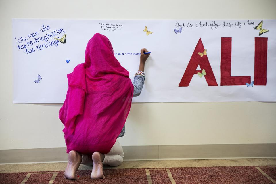 FILE - Zaina Piracha, 12, writes a message on a banner before an interfaith service at the Islamic Cultural Center of Louisville following the death of Muhammad Ali, in this Sunday, June 5, 2016, file photo. A new documentary looks at the city that raised Muhammad Ali, Louisville, Kentucky, and the week of his funeral, when the community came together to celebrate the legacy of “The Greatest.” (AP Photo/David Goldman, File)