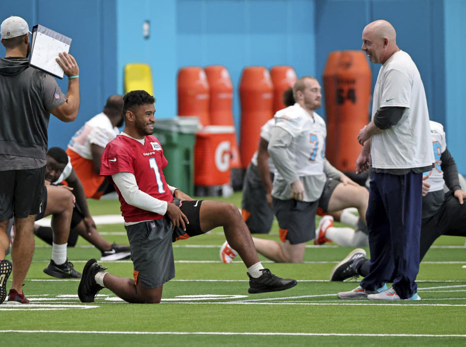 Miami Dolphins co-offensive coordinator George Godsey talks with Dolphins quarterback Tua Tagovailoa (1) during NFL football practice in Miami Gardens, Fla., Wednesday, Oct. 20, 2021. The Atlanta Falcons play at Miami on Sunday. (David Santiago/Miami Herald via AP)