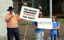 Protesters hold signs as U.S. President Barack Obama's motorcade passes upon his arrival in Roseburg, Oregon October 9, 2015. REUTERS/Kevin Lamarque