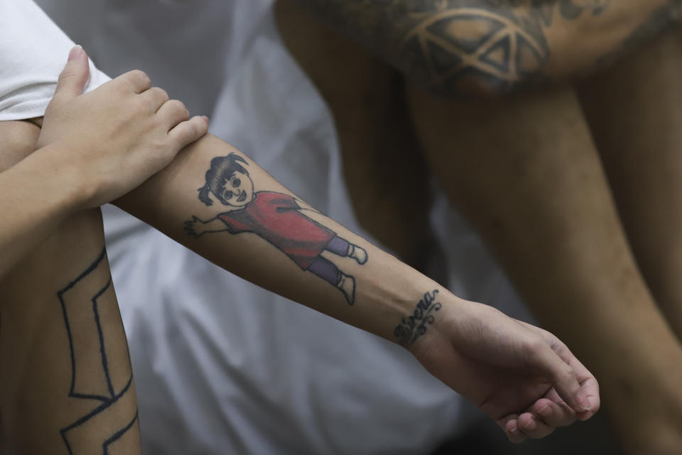 An inmates's arm features a tattoo of a youth as he attends a class on social behavior during a press tour of the Terrorism Confinement Center, a mega-prison in Tecololuca, El Salvador, Thursday, Oct. 12, 2023. (AP Photo/Salvador Melendez)