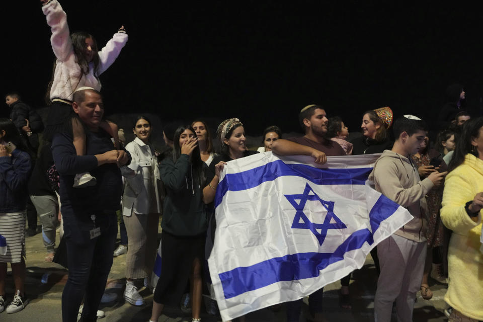 People wave to the convoy carrying newly released hostages from the Gaza Strip, in Ofakim, Israel on Sunday, Nov. 26, 2023. (AP Photo/Tsafrir Abayov)