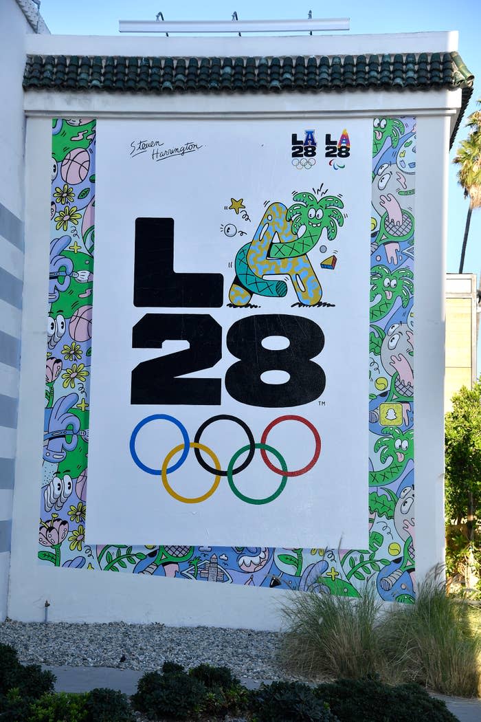 Mural featuring the LA 28 Olympics logo with Olympic rings and colorful cartoon illustrations. Signature of artist Steven Harrington visible