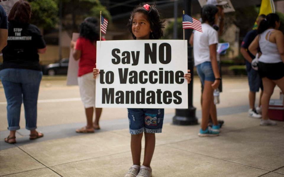 Anti-vaccine rally protesters hold signs outside of Houston Methodist Hospital - Mark Felix/AFP