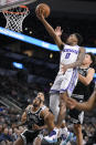 Sacramento Kings' Malik Monk (0) goes to the basket against San Antonio Spurs' Isaiah Roby, right, during the first half of an NBA basketball game, Wednesday, Feb. 1, 2023, in San Antonio. (AP Photo/Darren Abate)