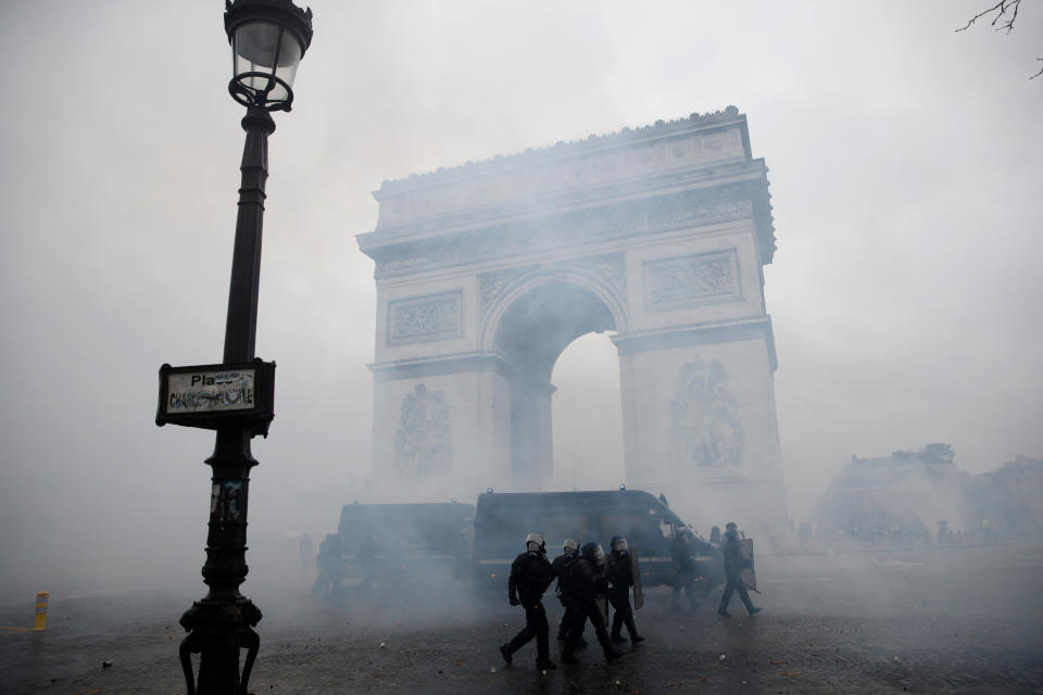 French riot police pass by the Arc de Triomphe as they clash with protesters wearing yellow vests during a demonstration over high fuel prices in Paris, Dec. 1, 2018. (Photo: Yoan Valat/EPA-EFE/REX/Shutterstock)