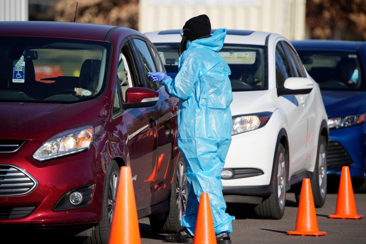 A medical technician performs a nasal swab test on a motorist queued up in a line at a COVID-19 testing site in Denver on Dec. 30, 2021.