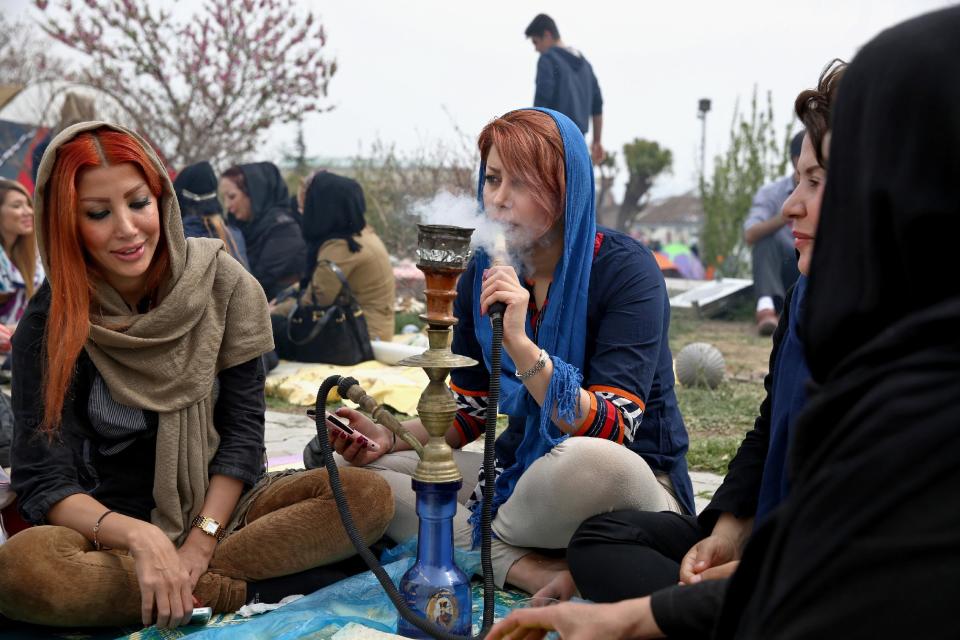 An Iranian woman smokes a water pipe with family members observing the ancient festival of Sizdeh Bedar, an annual public picnic day on the 13th day of the Iranian new year, west of Tehran, Iran, Wednesday, April 2, 2014. Sizdeh Bedar, which comes from the Farsi words for “thirteen” and “day out,” is a legacy from Iran’s pre-Islamic past that hard-liners in the Islamic Republic never managed to erase from calendars. Many say it’s bad luck to stay indoors for the holiday. (AP Photo/Ebrahim Noroozi)