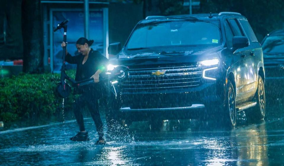 Jueves 13 de junio de 2024: Una mujer que lleva su "scooter" siendo empapada por una fuerte lluvia mientras cruza Biscayne Boulevard y 14 Street al tiempo que una condición climática severa sigue afectando el sur de la Florida. Pedro Portal/pportal@miamiherald.com