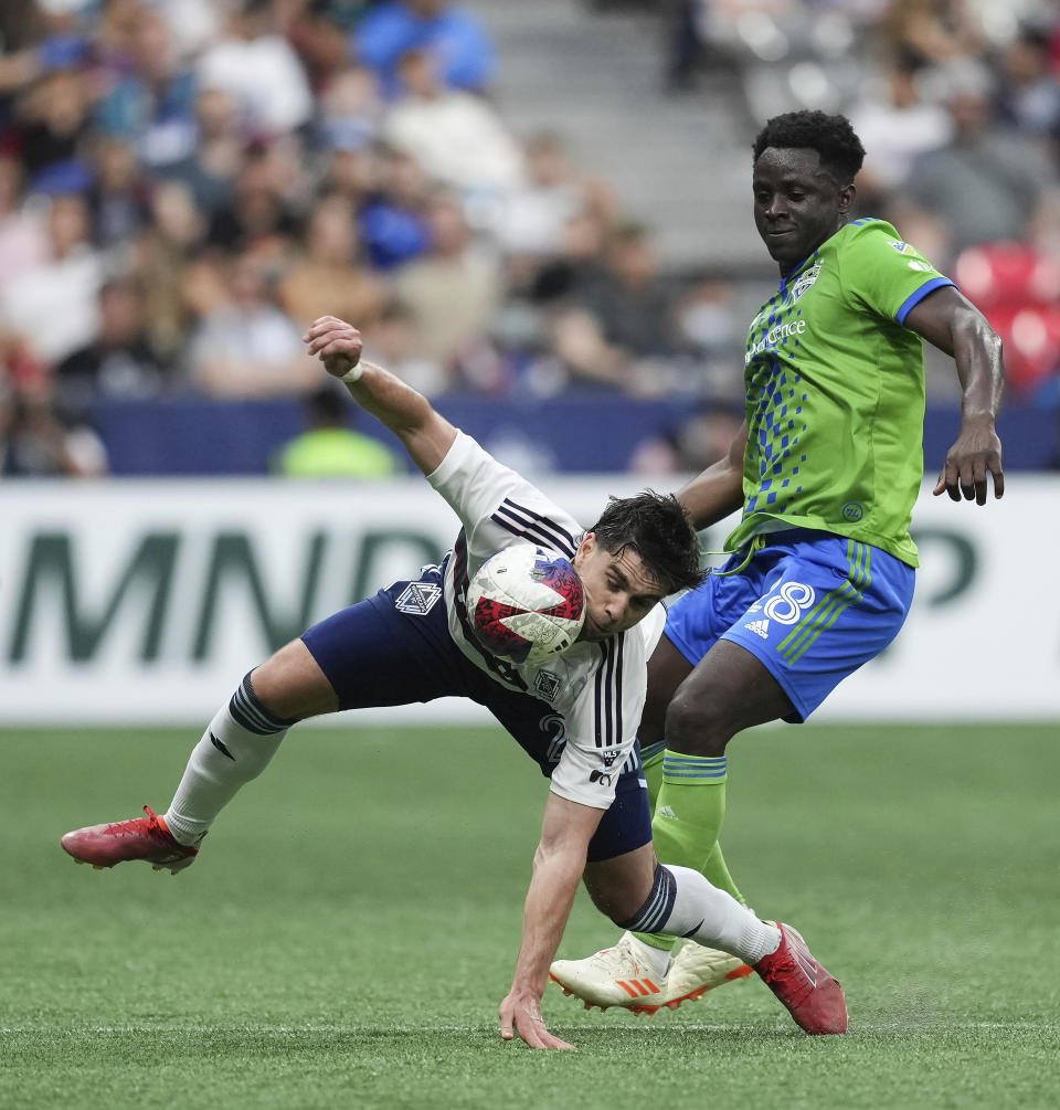 Vancouver Whitecaps' Brian White, front left, and Seattle Sounders' Yeimar Gomez vie for the ball during the first half of an MLS soccer match in Vancouver, British Columbia on Saturday, May 20, 2023. (Darryl Dyck/The Canadian Press via AP)